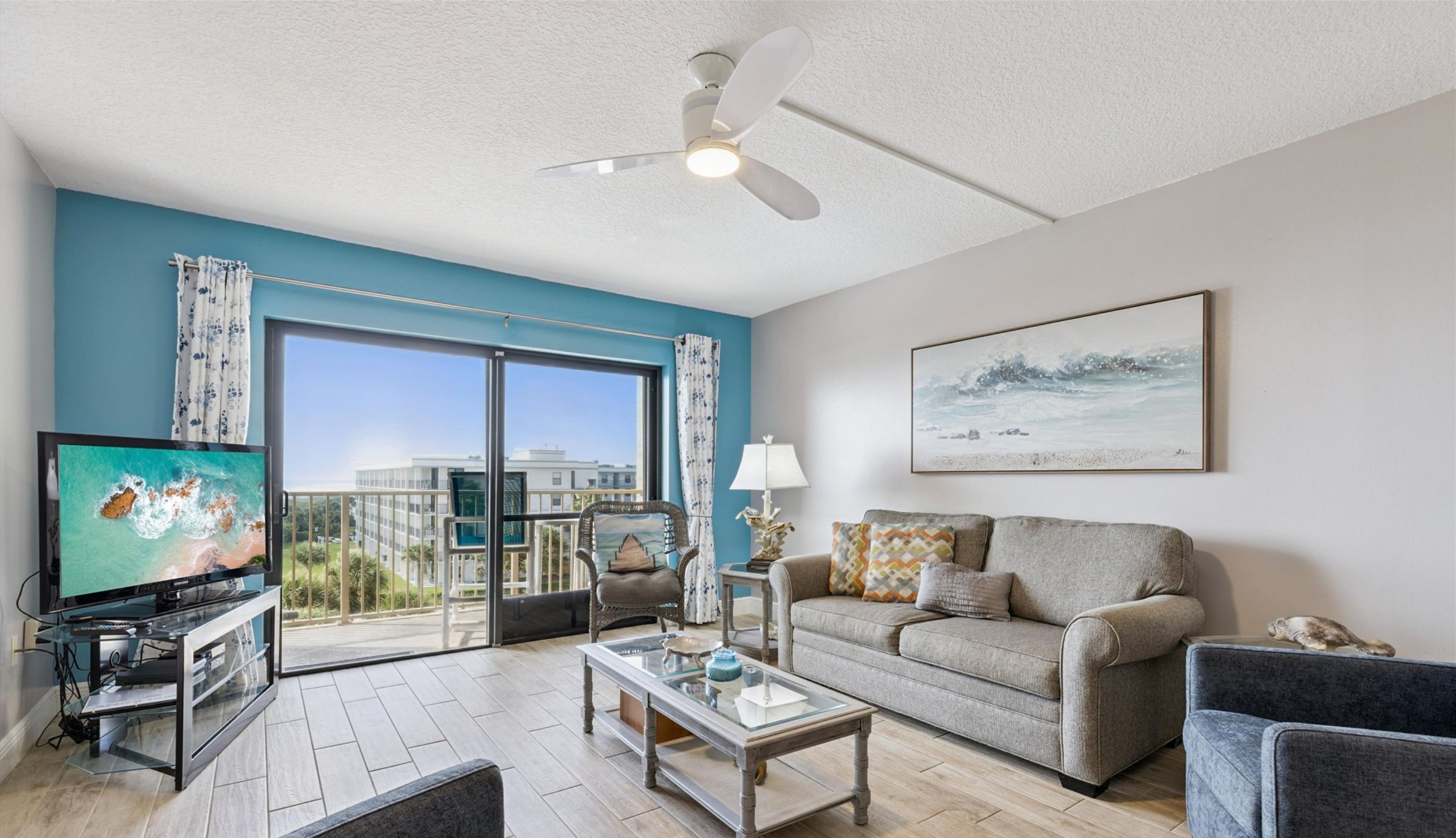 A living room with a sofa, TV, and a balcony with a view.