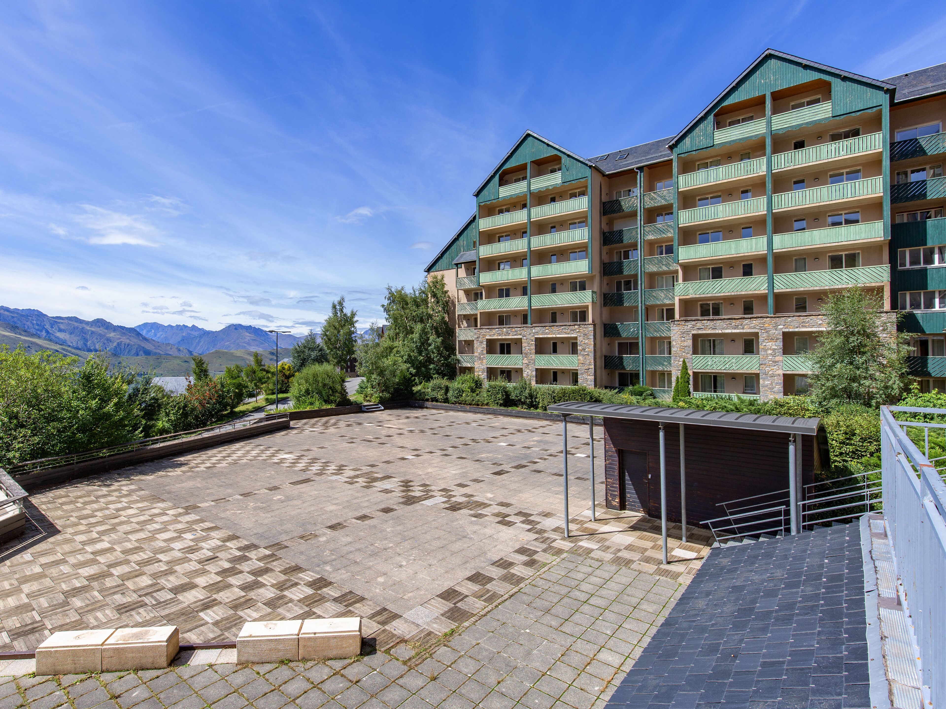 Un hotel de varios pisos con terraza en la azotea, fachada de piedra y balcones.