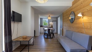 Una sala de estar moderna con un sofá, una mesa de comedor y un televisor.