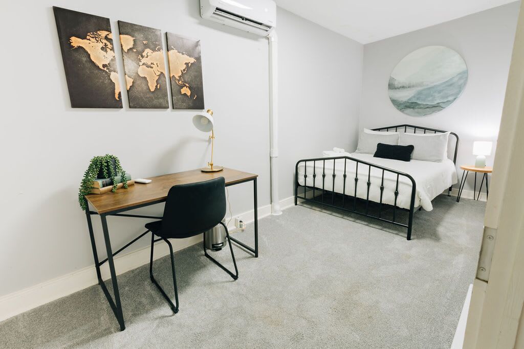 Una camera da letto con un letto, una scrivania con una sedia, una mappa del mondo appesa al muro e un quadro rotondo.