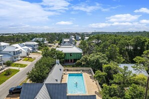 Un quartier résidentiel avec des maisons modernes, une piscine et un bâtiment écologique doté d’un toit en métal.