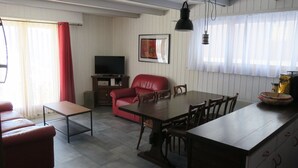 A room with a dining table, red leather sofa, TV, and a framed picture on the wall.