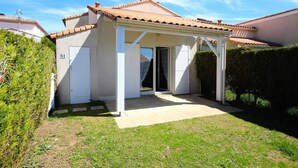 A small, single-story house with a tiled roof, a covered patio area, and a number '41' sign on the door.