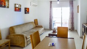 Ein Wohnzimmer mit einer Couch, einem Esstisch, Stühlen und Kunstwerken an den Wänden.