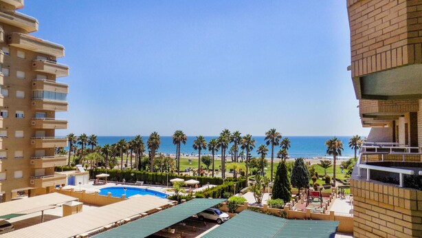 Ein Hotel mit Pool, Strandblick und Palmen.
