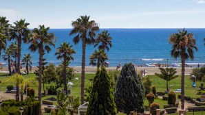 Blick auf einen Strand mit Palmen, blauem Himmel und ruhiger See.