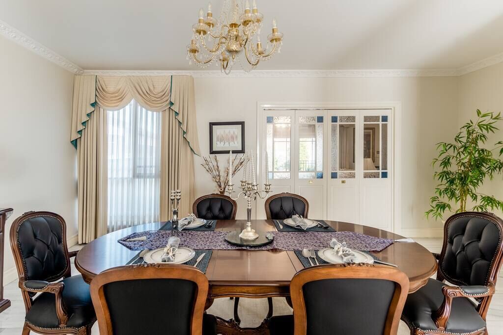 Une salle à manger avec une table ronde, six chaises et un lustre.