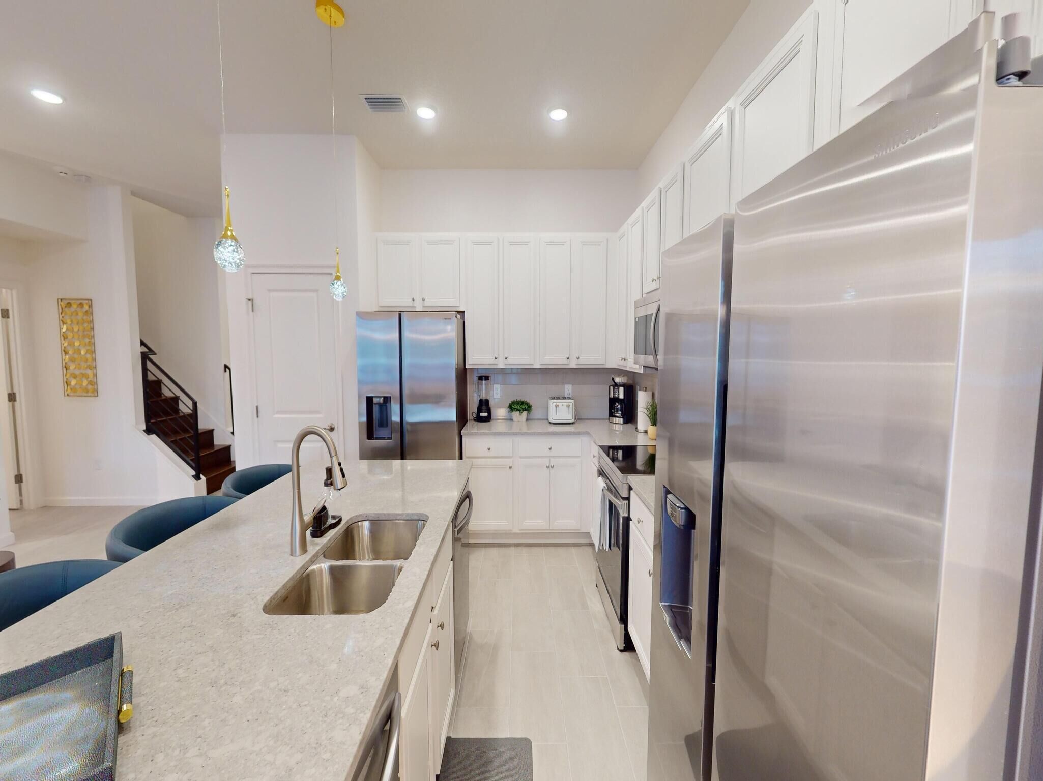 A modern kitchen with stainless steel appliances, white cabinetry, and a granite countertop.