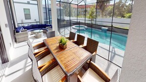 Un espace extérieur lumineux, aménagé pour les repas, avec une piscine, des meubles en osier et une vue sur les bâtiments environnants.