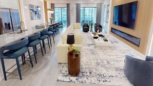 A modern living room with a sofa, coffee table, and TV. There is a dining area with a bar and chairs. - Bernie Pool Home 8 BED (Orlando)