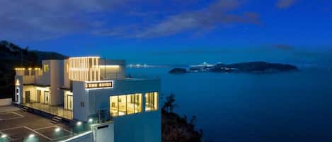 Un hotel moderno con una terraza en la azotea y vistas al mar, llamado "The Beige".