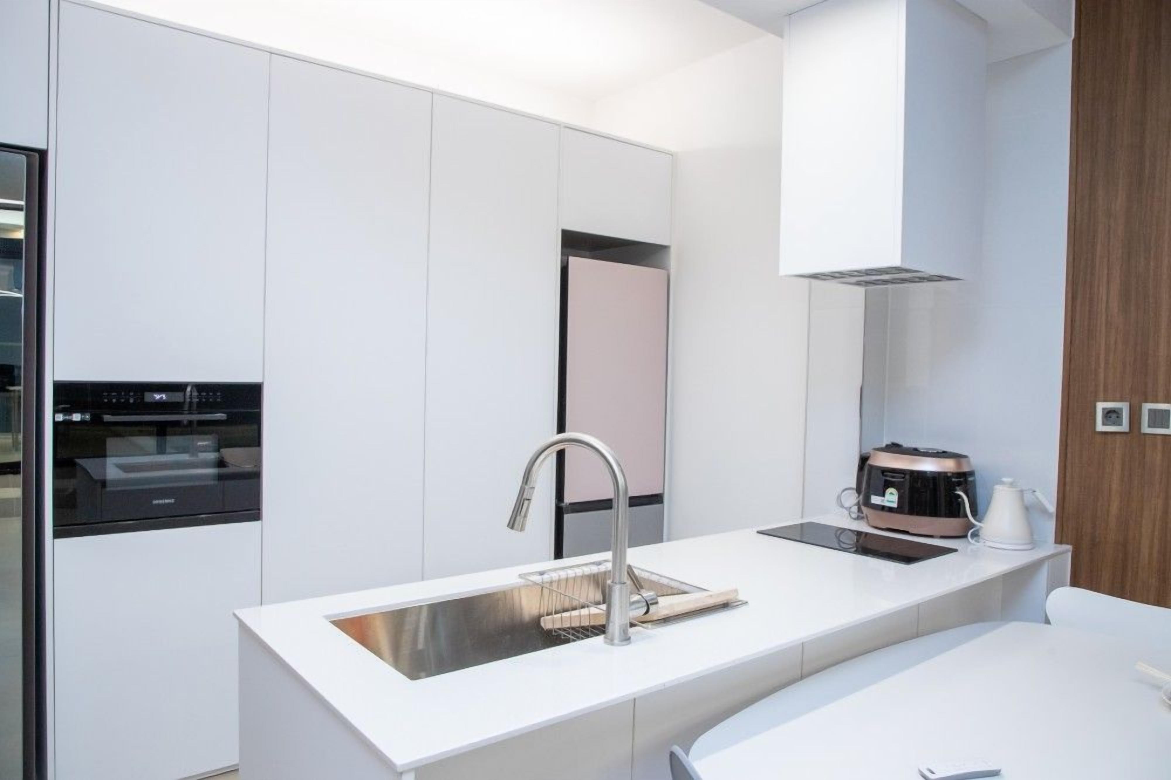 A modern kitchen with a built-in oven, a stainless steel sink, and a coffee maker.