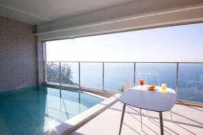 A modern indoor swimming pool with a clear view of the sea and cityscape. - The Beige (Geoje)