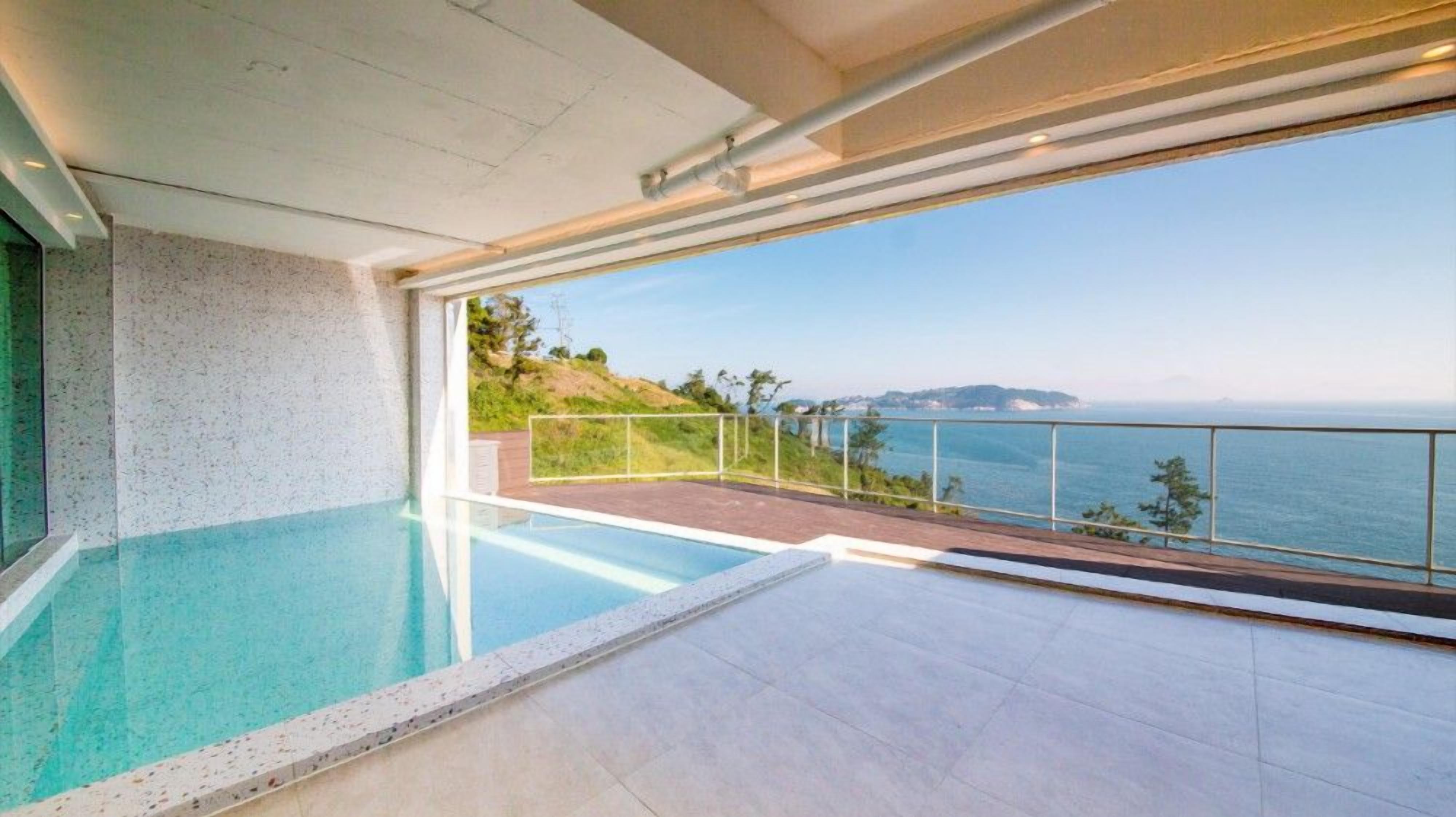 A modern infinity pool with a clear view of the sea and a distant island.
