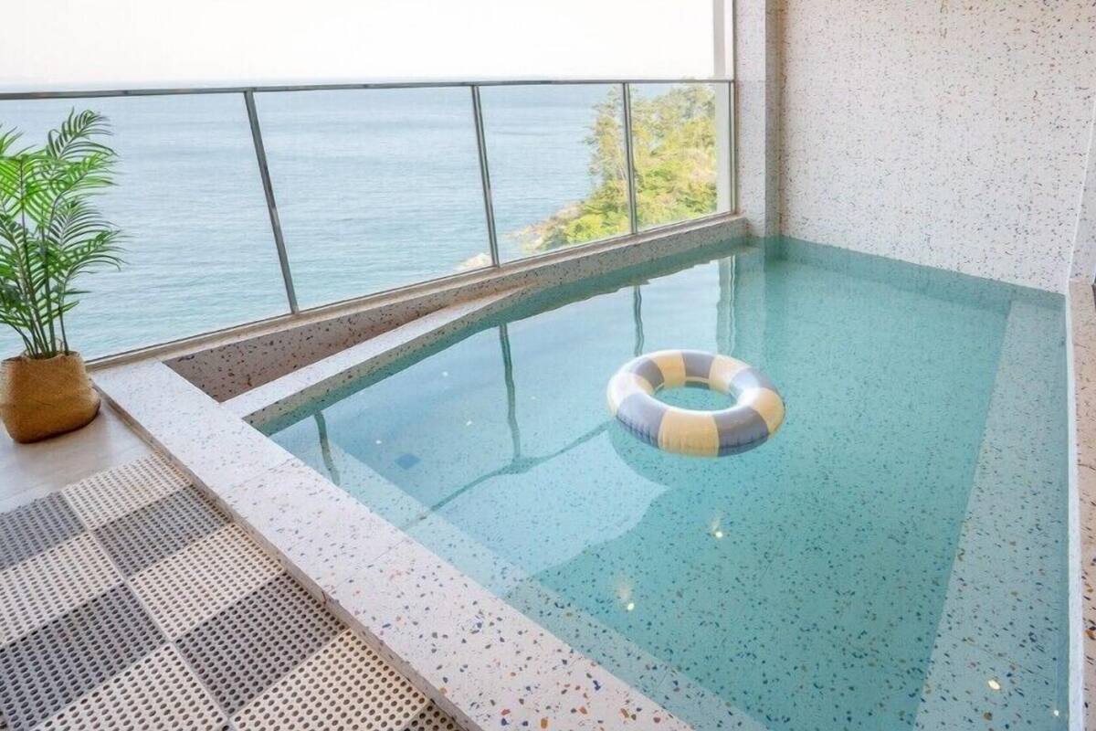 A small indoor swimming pool with a clear view of the sea through large windows.