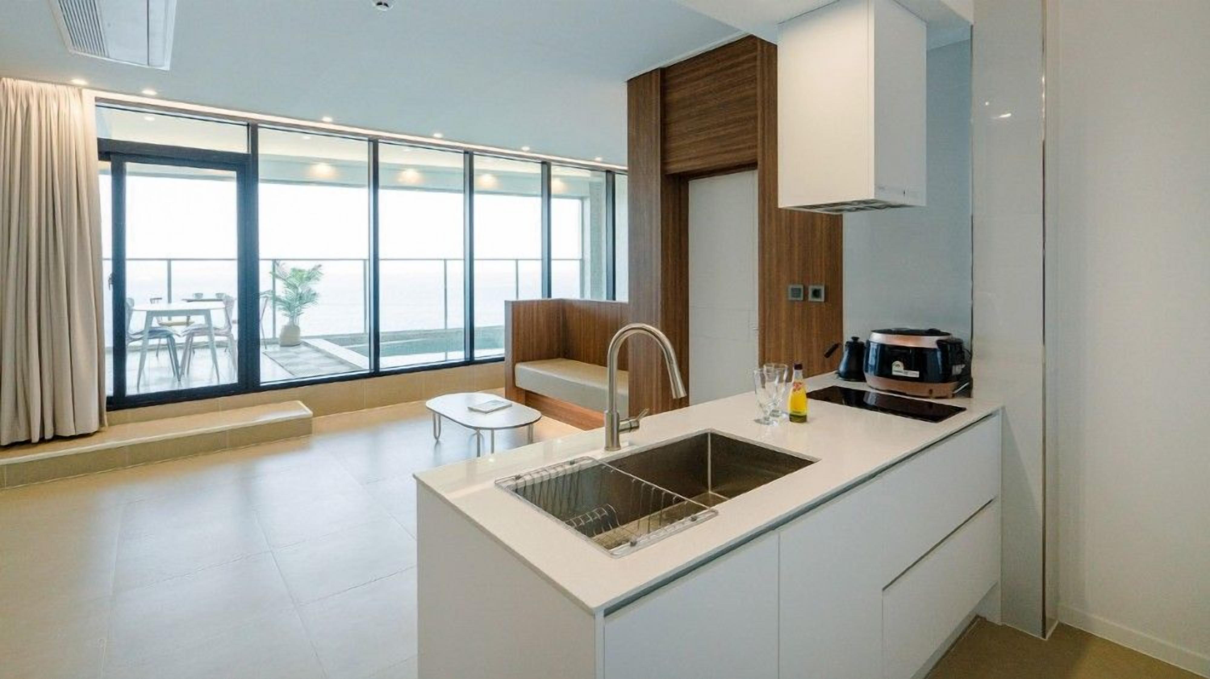 A modern kitchen with a large window, a built-in sink, and a dining area with a bench.