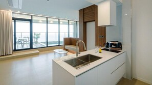 A modern kitchen with a large window, a built-in sink, and a dining area with a bench. - The Beige (Geoje)