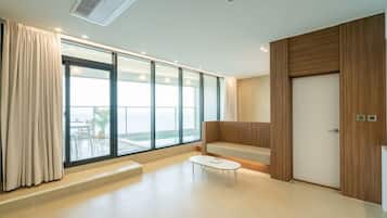 Een moderne hotelkamer met grote ramen, een zithoek en een houten garderobe.