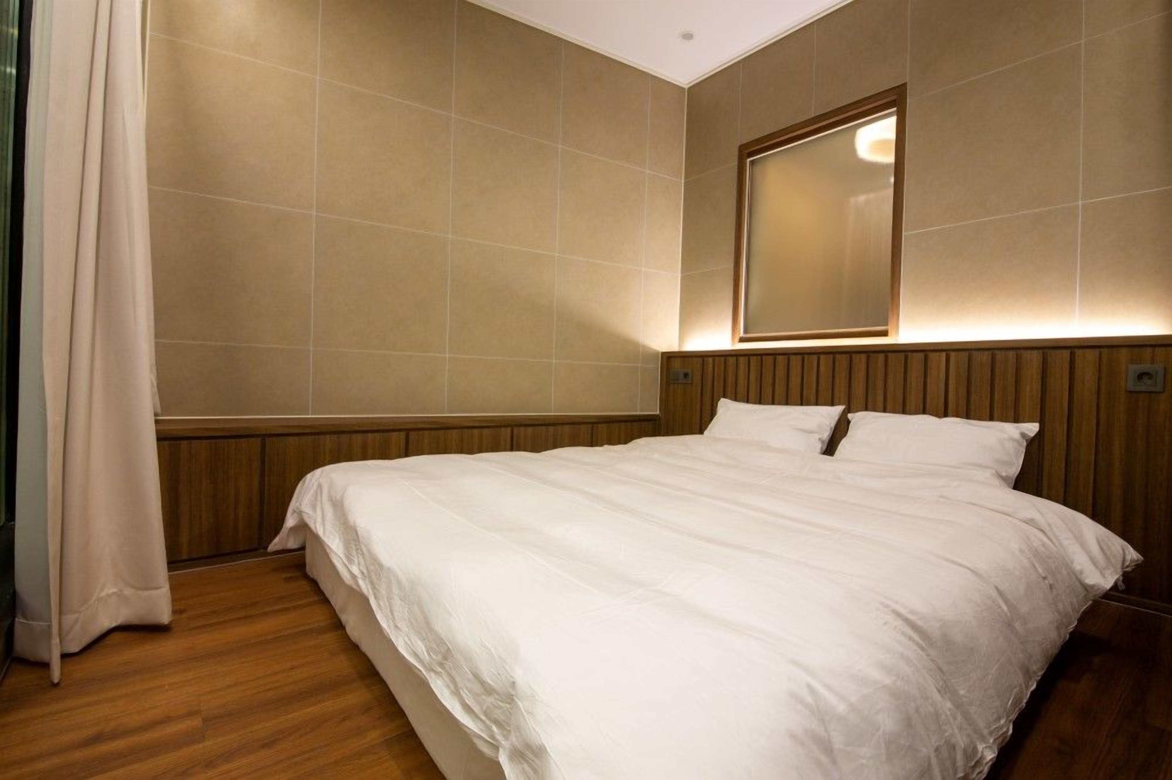 Habitación de hotel con una cama grande, cabecera de madera y un espejo en la pared.