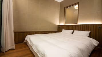 Habitación de hotel con una cama grande, cabecera de madera y un espejo en la pared.
