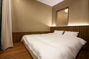 Habitación de hotel con una cama grande, cabecera de madera y un espejo en la pared.