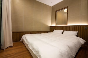 Habitación de hotel con una cama grande, cabecera de madera y un espejo en la pared.