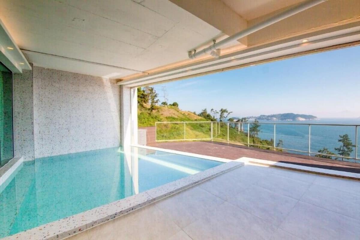 A modern infinity pool with a clear view of the sea and a distant island.