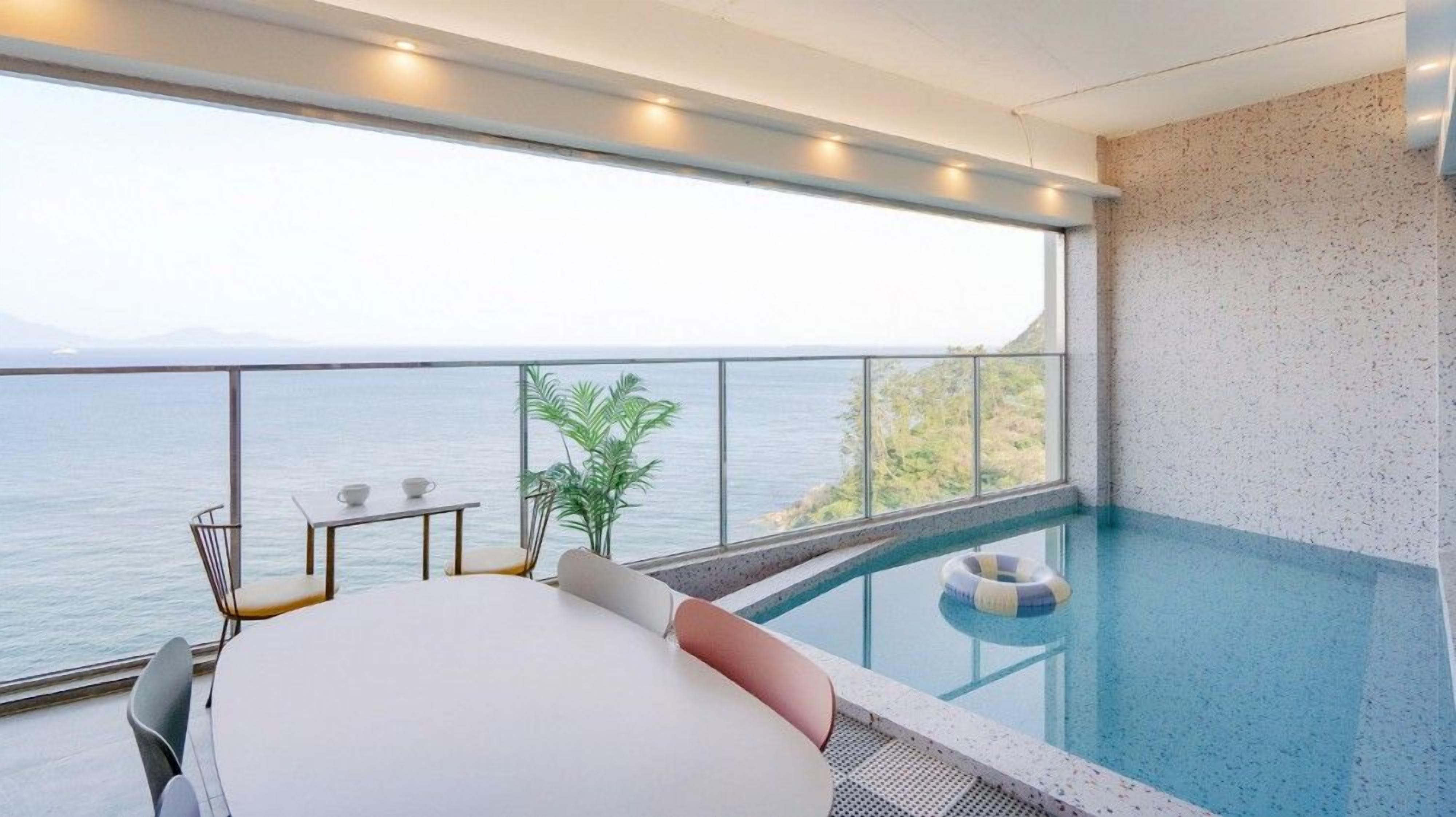 A balcony with a pool, a bed, and a view of the sea.