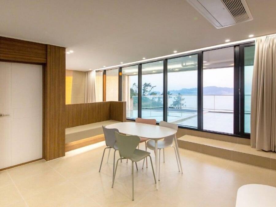 A modern room with a large window, a round table with chairs, and a wooden accent wall.