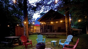 A backyard with a fire pit, outdoor seating, and a covered patio area. - Modern Rustic Retreat in Poconos (Greentown)
