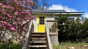 A house with a yellow door, wooden stairs, and a small porch. - Modern Rustic Retreat in Poconos (Greentown)