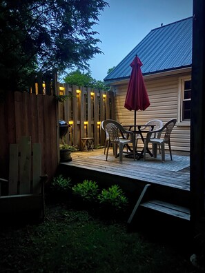 A wooden deck with a table and chairs, a red umbrella, and a wooden fence. - Modern Rustic Retreat in Poconos (Greentown)