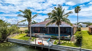 A house with a pool, a dock, and a kayak. - Where waters intersect and Dreams unwind! Kayak, Bikes, Heated Pool & Spa - Villa Cayman - Roelens (Cape Coral)