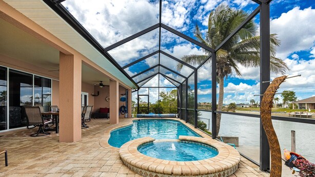 A covered swimming pool with a hot tub, outdoor seating, and a view of the water. - Where waters intersect and Dreams unwind! Kayak, Bikes, Heated Pool & Spa - Villa Cayman - Roelens (Cape Coral)