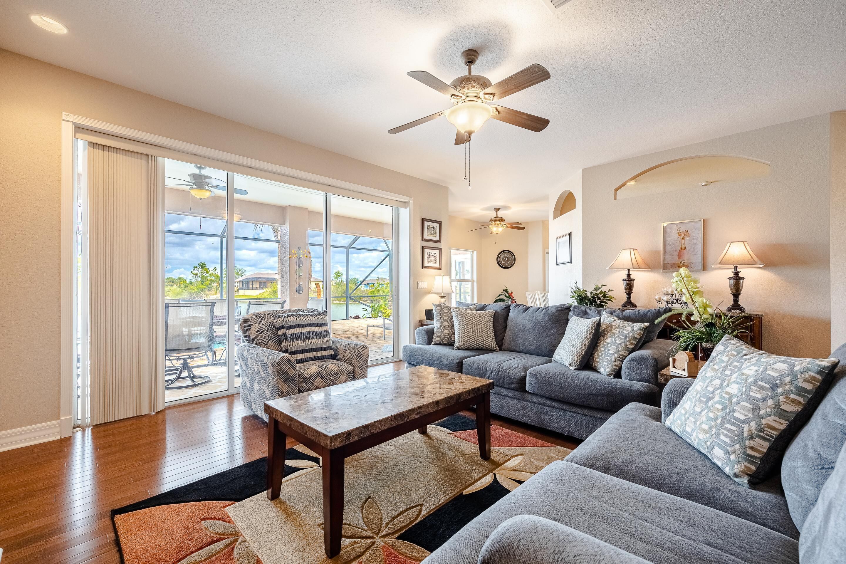 A spacious living room with a large gray sofa set, a wooden coffee table, and a ceiling fan.