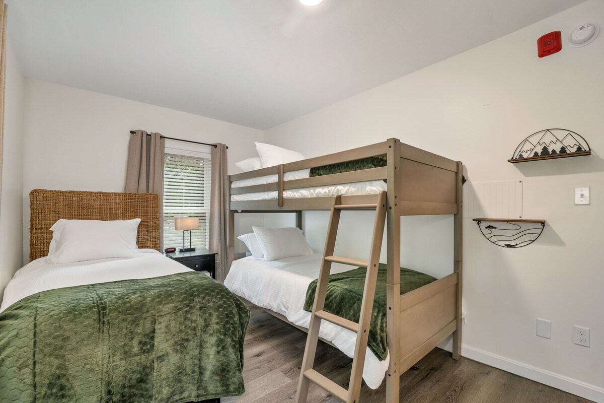 A bedroom with two beds, a ladder, a lamp, and decorative wall art.