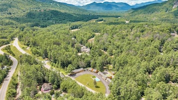 Une vaste zone boisée, traversée par une route et comprenant plusieurs bâtiments, dont une maison avec une piscine.