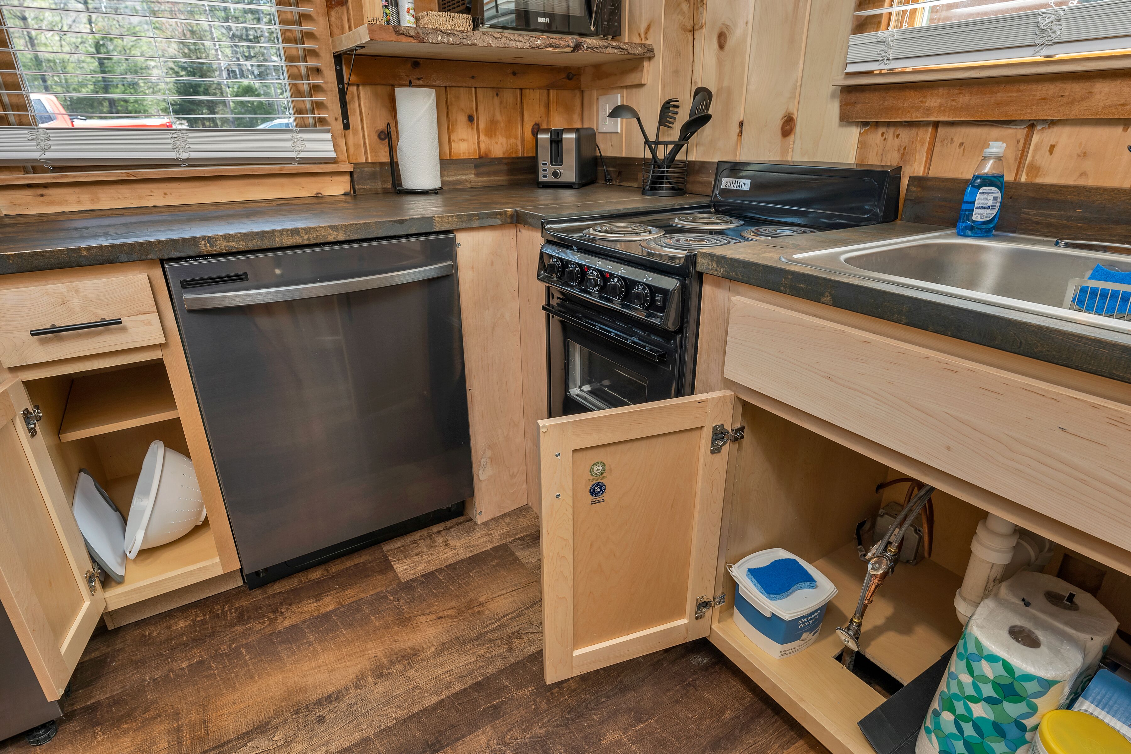 A compact kitchen with a dishwasher, stove, and sink.