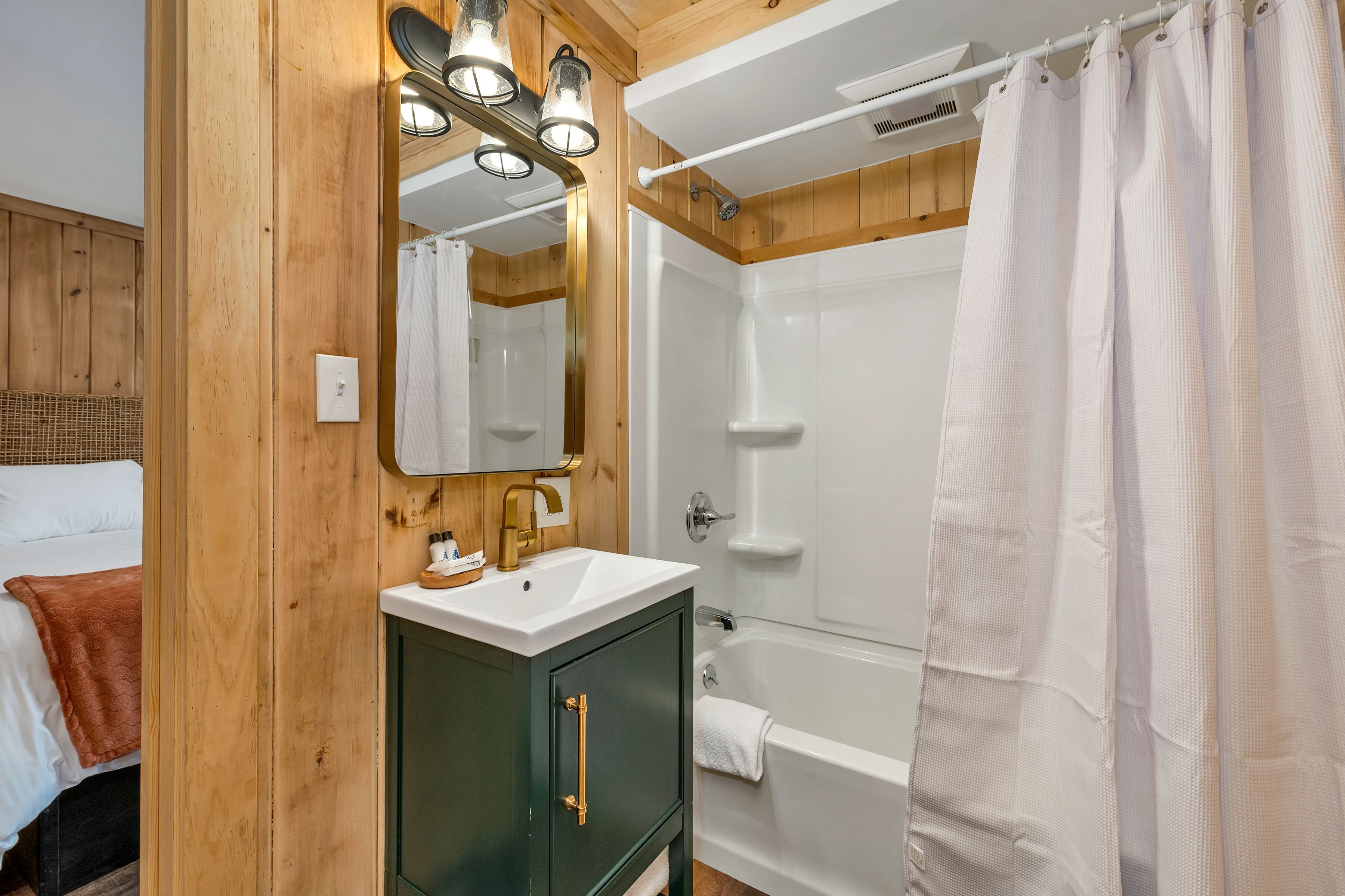 A wooden-paneled bathroom with a sink, mirror, and shower.