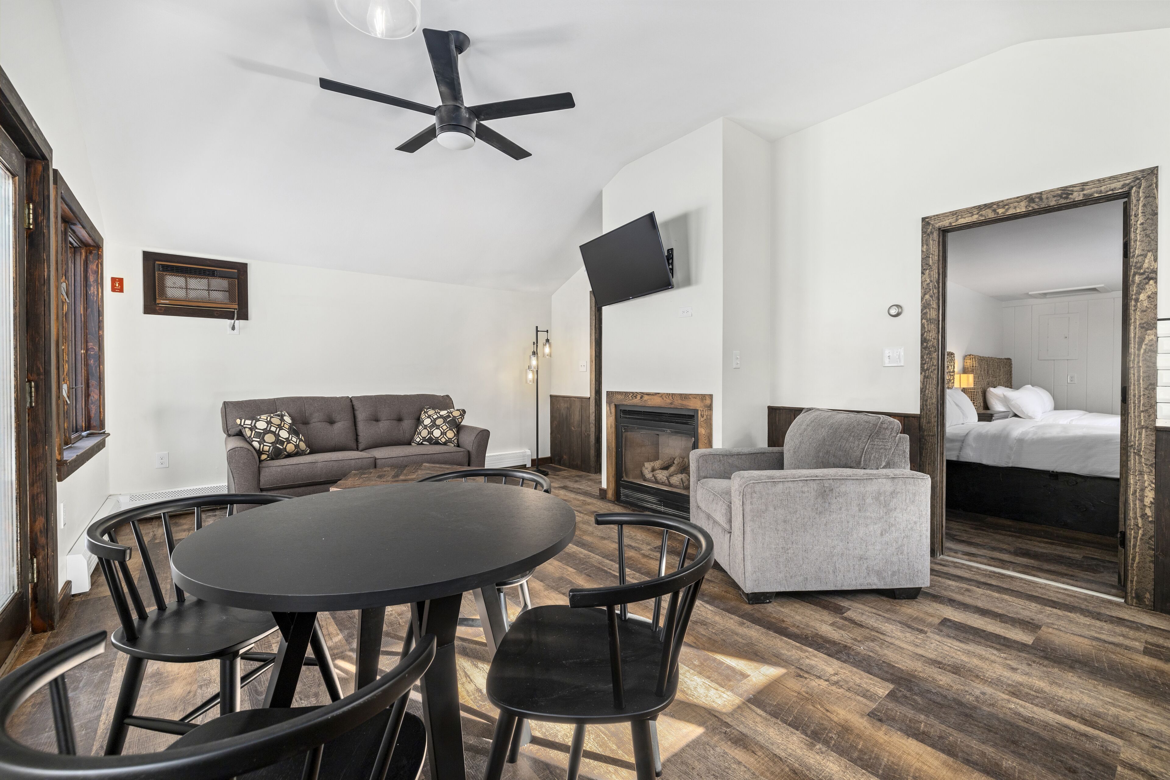 A modern living room with a round table, chairs, a sofa, a fireplace, and a large mirror.