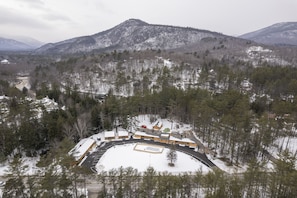 A snow-covered landscape with a building complex surrounded by trees and mountains.