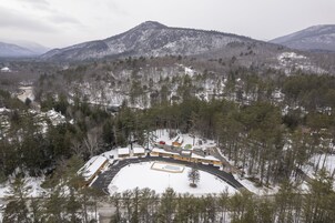 A snow-covered landscape with a building complex surrounded by trees and mountains.