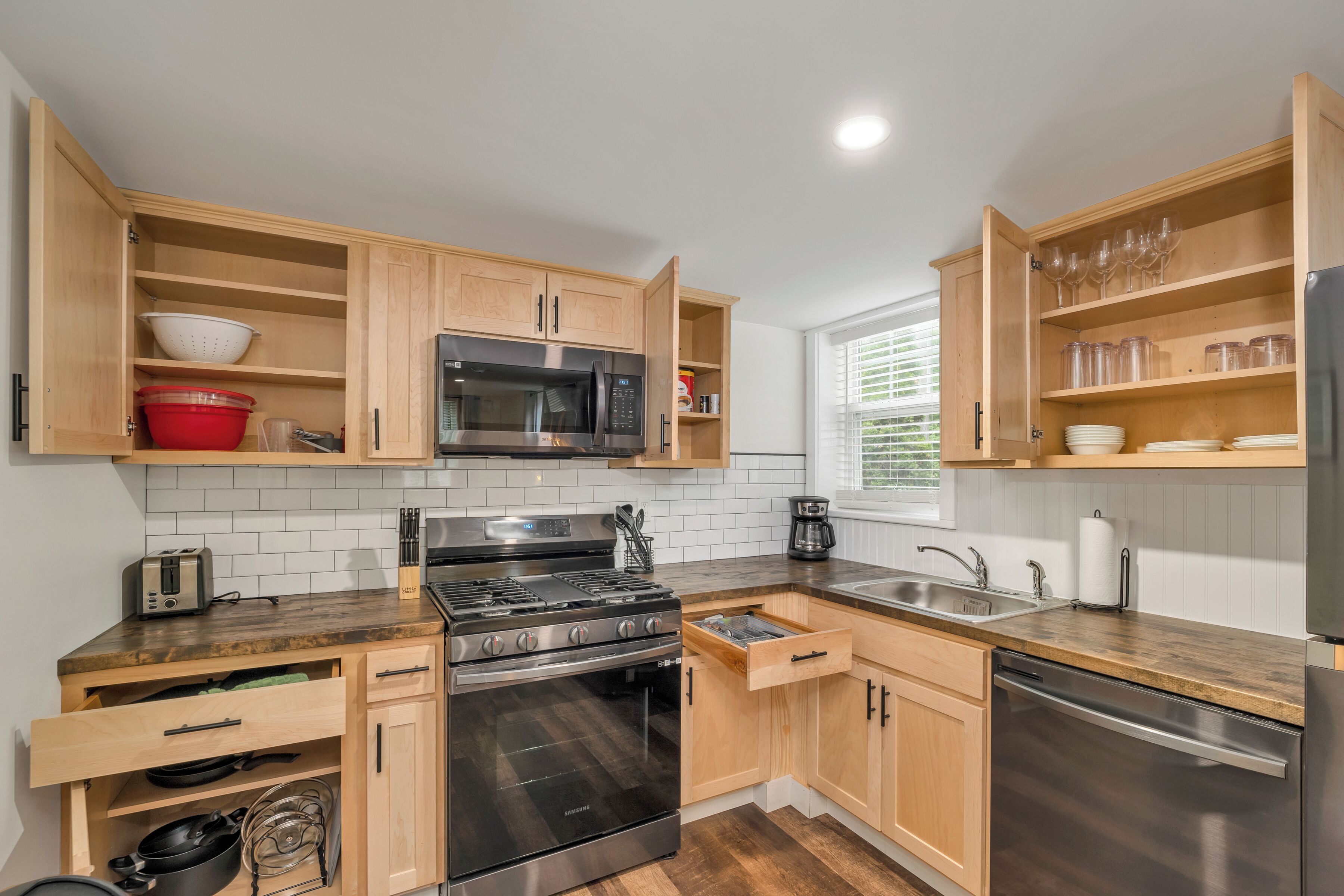 A modern kitchen with wooden cabinets, stainless steel appliances, and a window providing natural light.