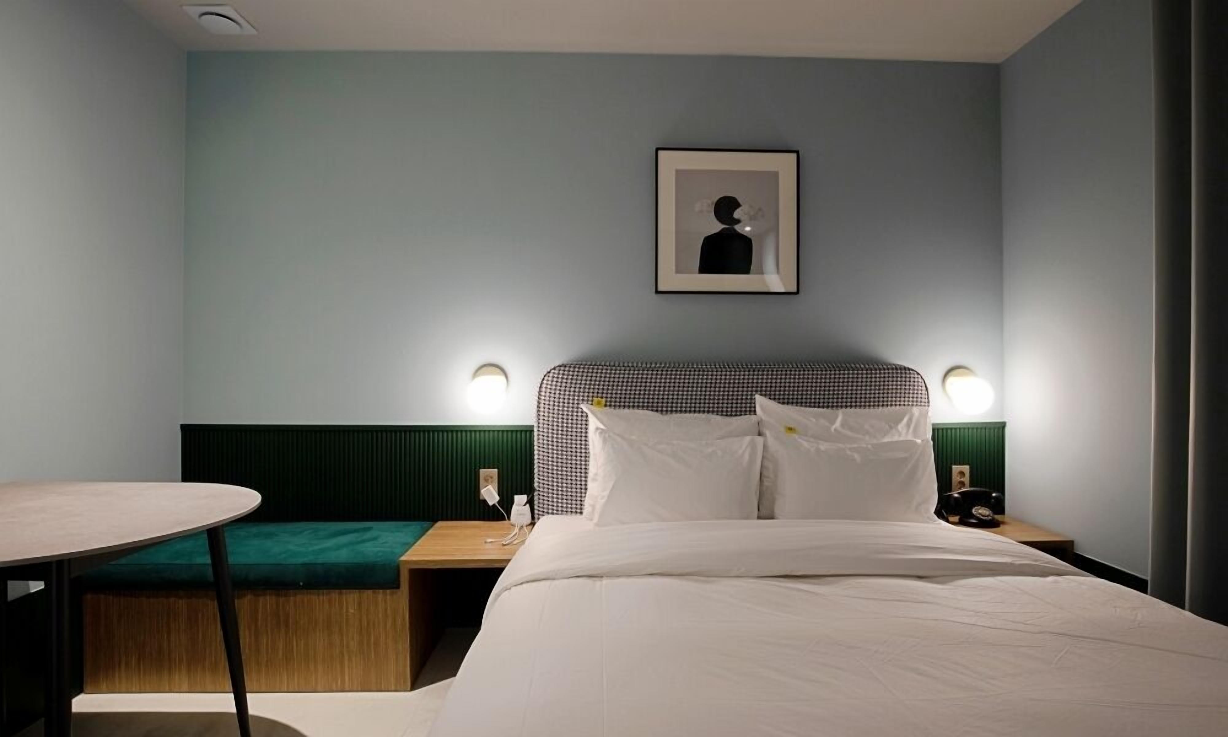 A hotel room with a bed, bedside tables, a desk, and a chair.