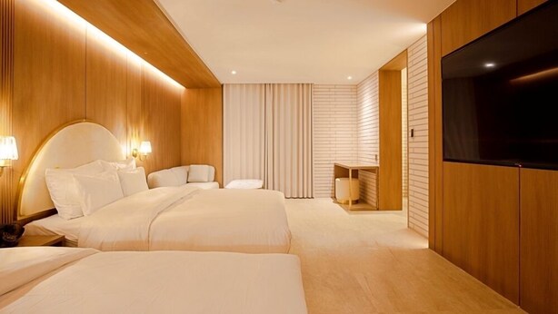 Ein modernes Hotelzimmer mit einem großen Bett, Nachttischen, einem Fernseher und einer Sitzecke.