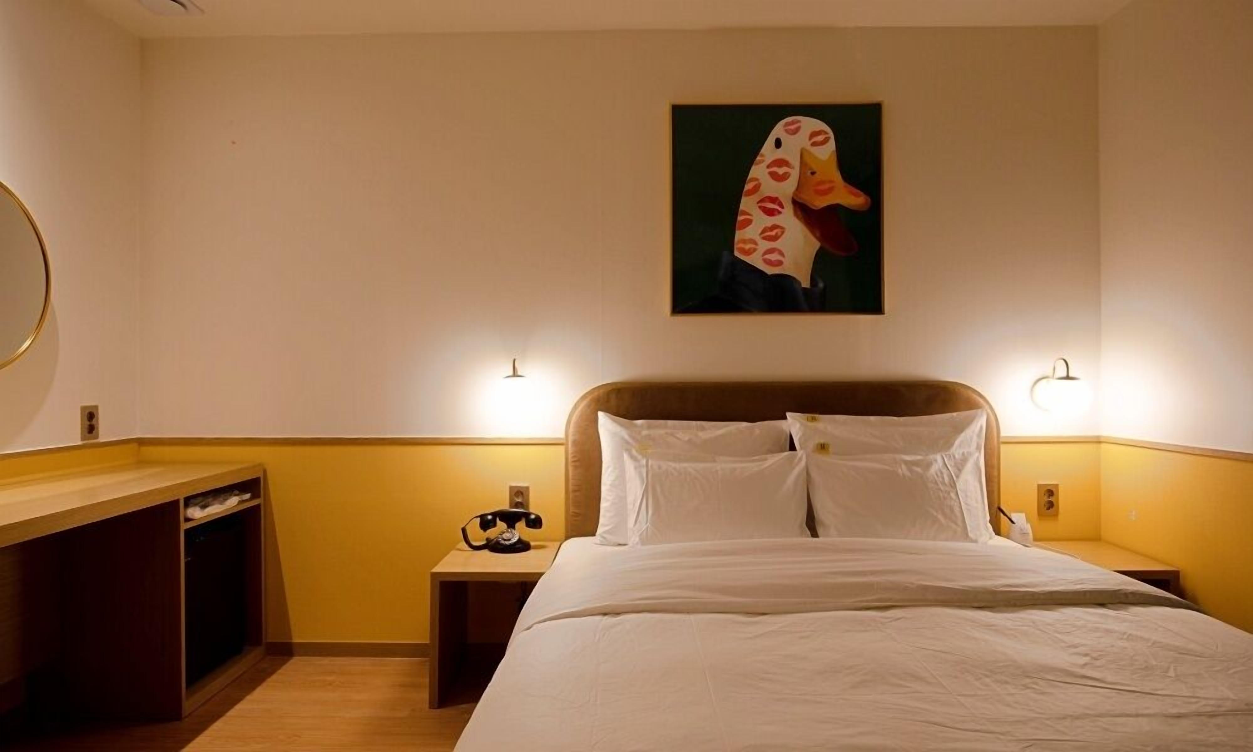 Een hotelkamer met een bed, nachtkastjes, een bureau en een schilderij aan de muur.