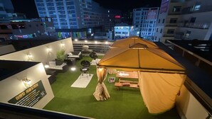 Eine Dachterrasse mit Zelt, Sitzgelegenheit und einem kleinen Tisch.