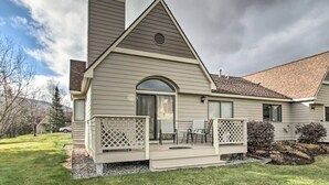 A single-story house with a gabled roof, a front porch with a lattice railing, and a small deck area.