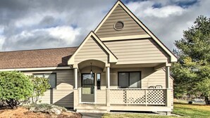 A single-story house with a gabled roof, a front porch with a lattice railing, and a small front yard with a pathway leading to the door.