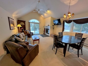 An open concept space with dining table that seats 4 and comfortable furniture that surrounds the wood-burning fireplace.